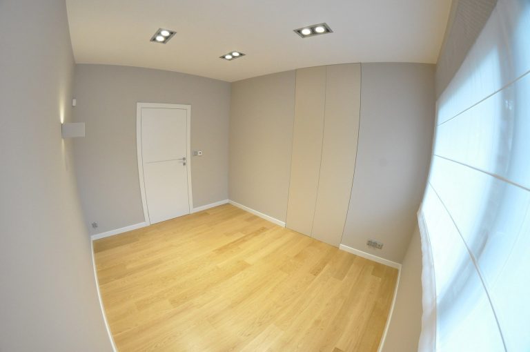 szary pokój z zabudową i panelami podłogowymi