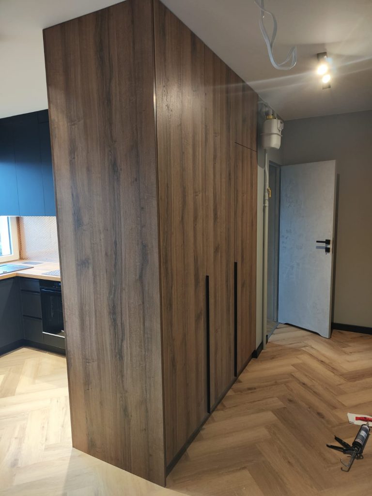 wykończenie wnętrza w mieszkaniu - panele w jodełkę, drzwi białe, zabudowa szafy