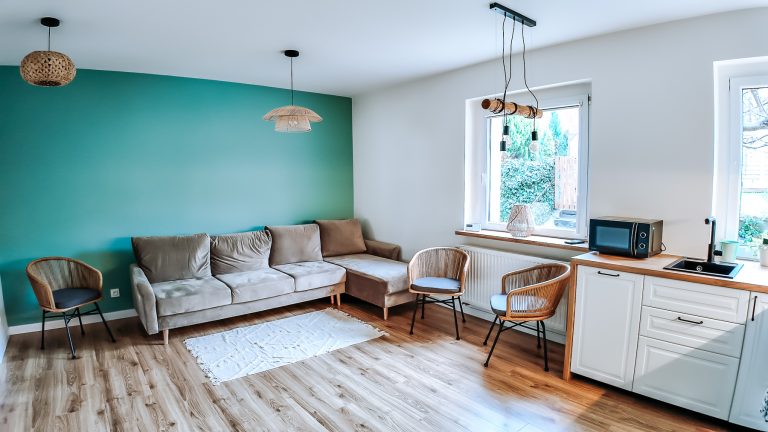 zielono - biały aneks kuchenny z drewnianą podłogą